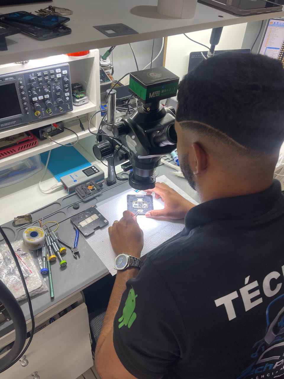 Técnico trabalhando em uma placa eletrônica sob microscópio